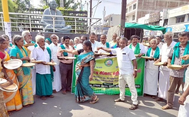 விவசாயிகள் நூதன முறையில் பாக்கு தட்டை கையில் ஏந்தி பிச்சை எடுத்து போராட்டம்